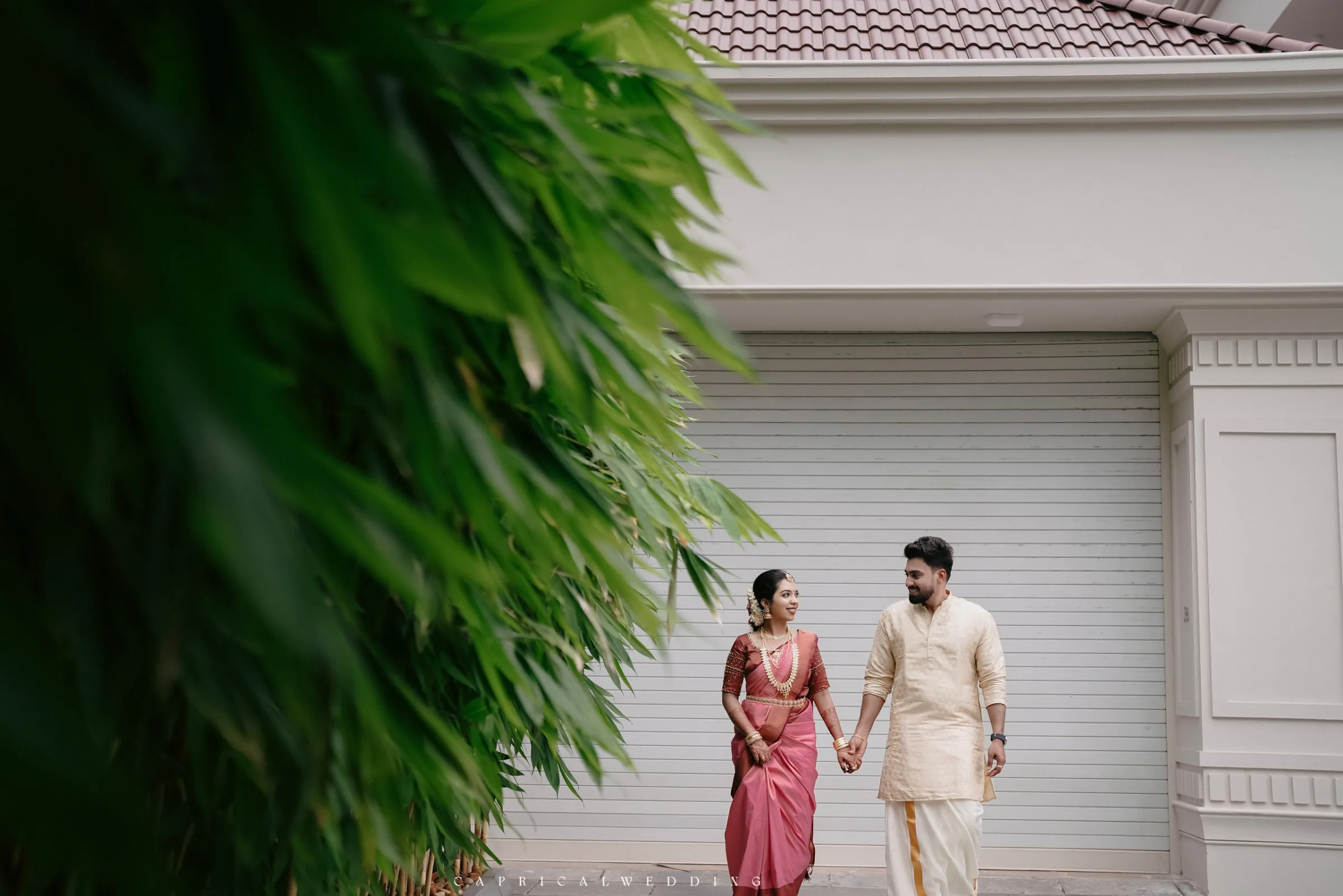 A couple walking together beside lush greenery
